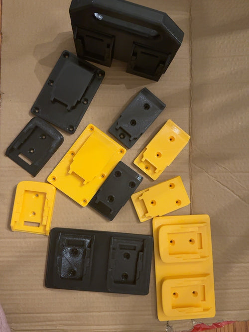 Black and yellow PETG DEWALT 20V MAX-compatible tool mounts, battery mounts, dual holders, and four-battery caddy arranged together